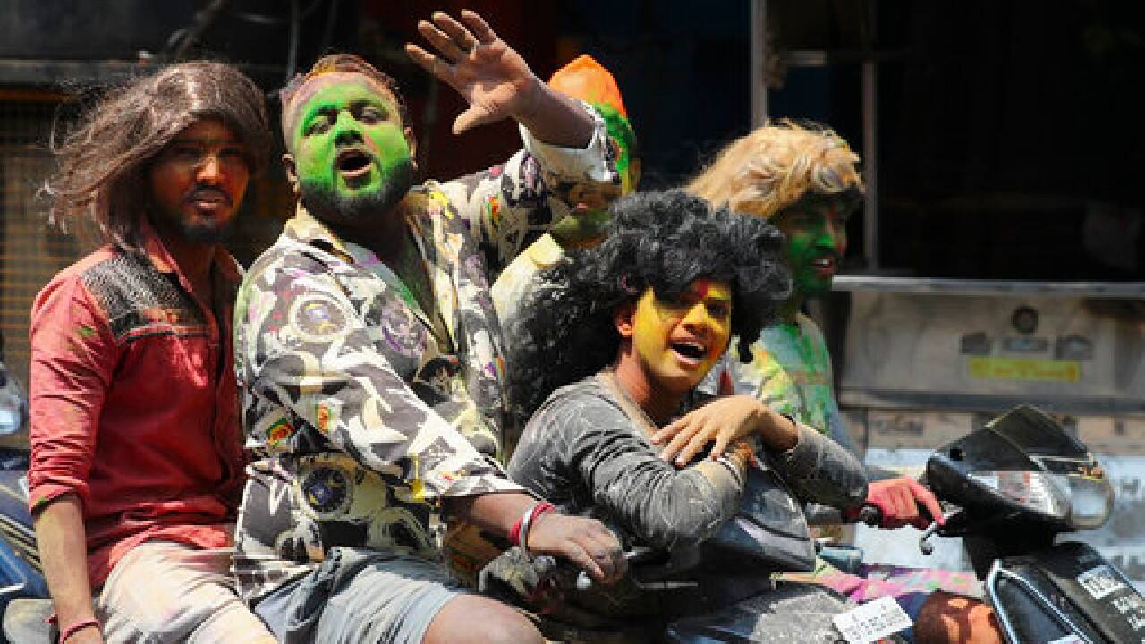 Revelers with their faces smeared with colored powder ride on motor bikes during Holi festivities in Hyderabad, India, March 29. (Image: AP)