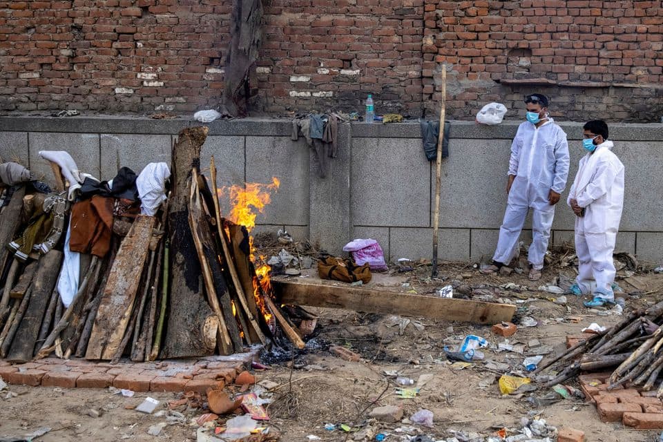 Relatives stand next to the burning funeral pyre of a person, who died due to the coronavirus disease (COVID-19), at a crematorium ground in New Delhi, India, April 22, 2021. REUTERS/Danish Siddiqui
