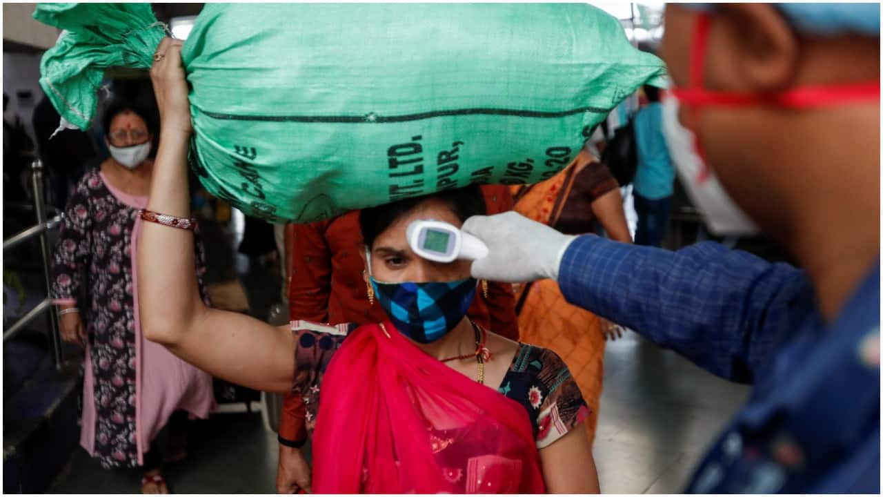 A health worker checks the temperature of a passenger at a railway station in Mumbai, Maharashtra on March 17, 2021. (Reuters)