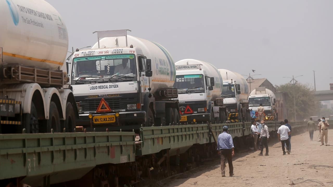 Empty oxygen tankers are loaded on a train wagon at the Kalamboli goods yard in Navi Mumbai, Maharashtra on April 19, 2021 before they are transported to collect liquid medical oxygen from other states. (Image: AP Photo/Rafiq Maqbool)