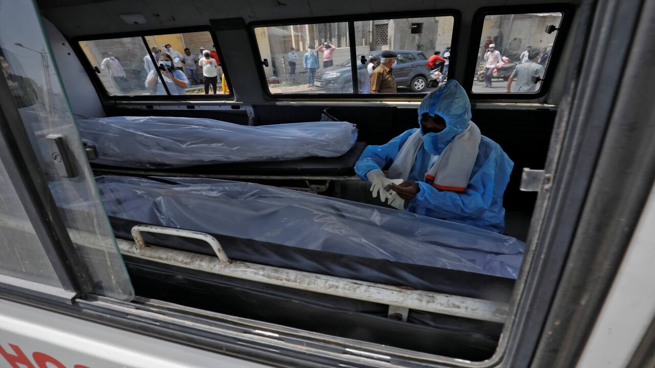A man wearing a protective suit sits next to the bodies of the victims of the coronavirus disease (COVID-19) inside an ambulance at a mortuary of a COVID-19 hospital in Ahmedabad. (Image: Reuters) A man wearing a protective suit sits next to the bodies of the victims of the coronavirus disease (COVID-19) inside an ambulance at a mortuary of a COVID-19 hospital in Ahmedabad. (Image: Reuters)