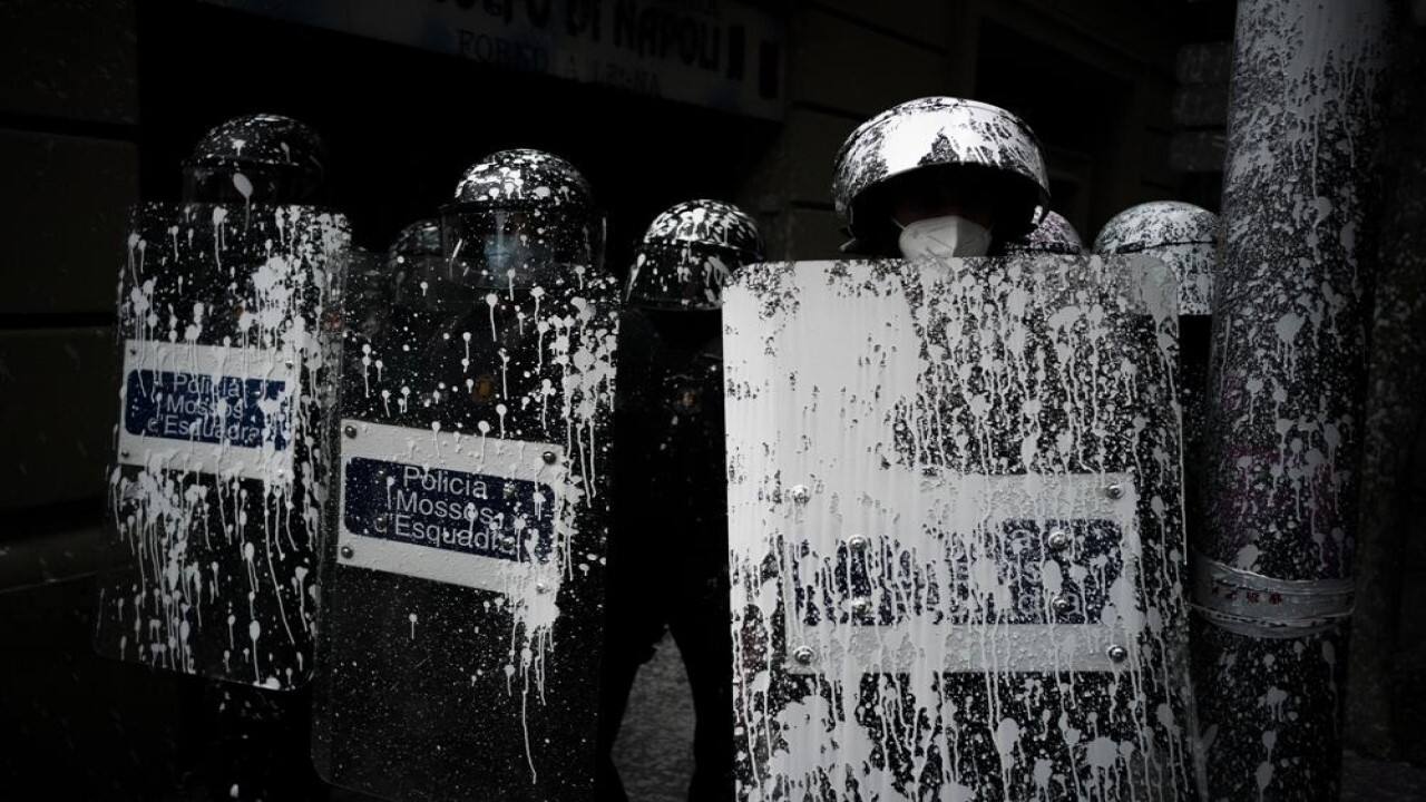 Riot police officers covered by paint thrown by protesters stand guard as activists try to stop the eviction of Axel Altadill, 28 from his apartment in Barcelona, Spain, Tuesday, May 25, 2021. Altadill has been accused of squatting in the apartment since January 2019. (Image: AP)