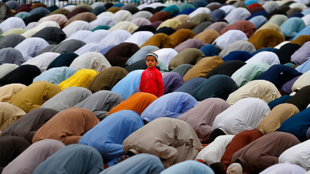 A Muslim boy stands beside his father performing an Eid al-Fitr prayer along with others at a ground in Rawalpindi, Pakistan, May 13. Millions of Muslims across the world are marking a muted and gloomy holiday of Eid al-Fitr, the end of the fasting month of Ramadan, a usually joyous three-day celebration that has been significantly toned down as coronavirus cases soar. (Image: AP/Anjum Naveed)