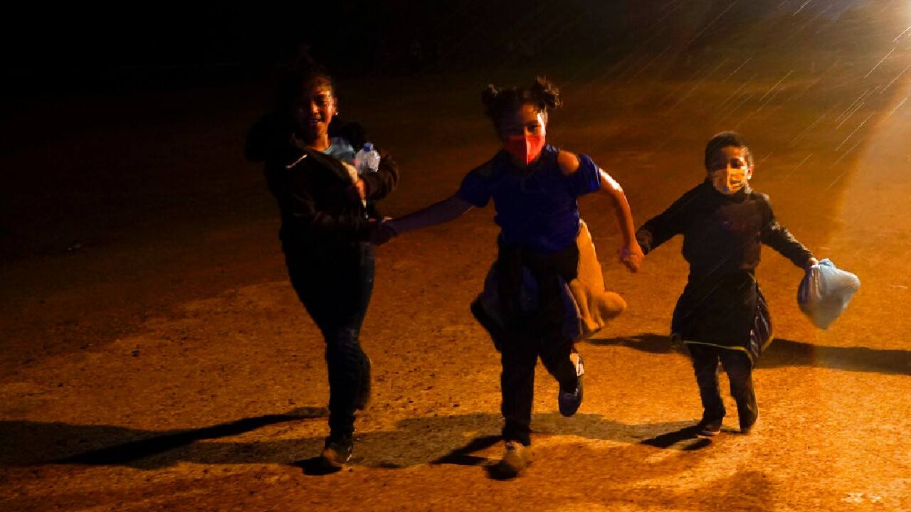 Three young migrants hold hands as they run in the rain at an intake area after turning themselves in upon crossing the U.S.-Mexico border, May 11, in Roma, Texas. The number of unaccompanied children encountered on the U.S. border with Mexico in April eased from an all-time high a month earlier, while more adults were found coming without families, authorities said on May 11. (Image: AP/Gregory Bull)