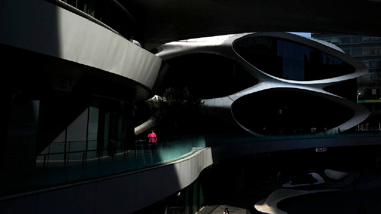 A beam of sunlight is cast on people wearing face masks to help curb the spread of the coronavirus as they walk through the Galaxy Soho commercial office building in Beijing, May 10. (Image: AP/Andy Wong)