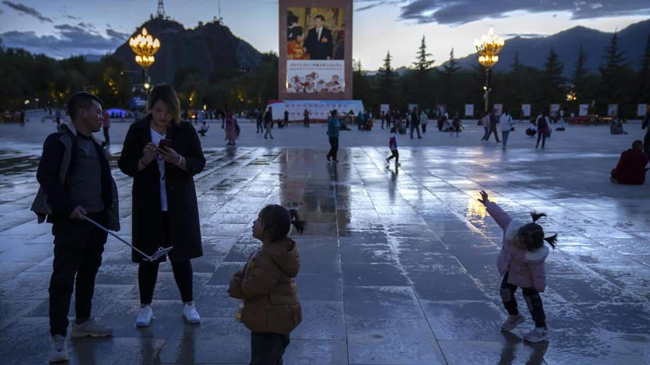 Tourists stand near a large mural depicting Chinese President Xi Jinping on a square near the Potala Palace in Lhasa in western China's Tibet Autonomous Region, Tuesday, June 1, 2021. Tourism is booming in Tibet as more Chinese travel in-country because of the coronavirus pandemic, posing risks to the region's fragile environment and historic sites. (AP Photo/Mark Schiefelbein) Tourists stand near a large mural depicting Chinese President Xi Jinping on a square near the Potala Palace in Lhasa in western China's Tibet Autonomous Region, Tuesday, June 1, 2021. Tourism is booming in Tibet as more Chinese travel in-country because of the coronavirus pandemic, posing risks to the region's fragile environment and historic sites. (AP Photo/Mark Schiefelbein)