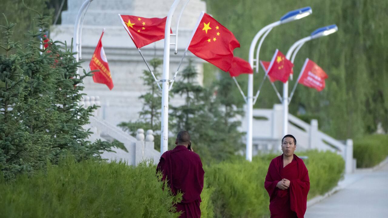 In this May 31, 2021, file photo, monks walk along a sidewalk path lined with Chinese flags at the Tibetan Buddhist College near Lhasa in western China's Tibet Autonomous Region as seen during a government organized visit for foreign journalists. High-pressure tactics employed by China's ruling Communist Party appear to be finding success in separating Tibetans from their traditional Buddhist culture and the influence of the Dalai Lama. (AP Photo/Mark Schiefelbein, File)