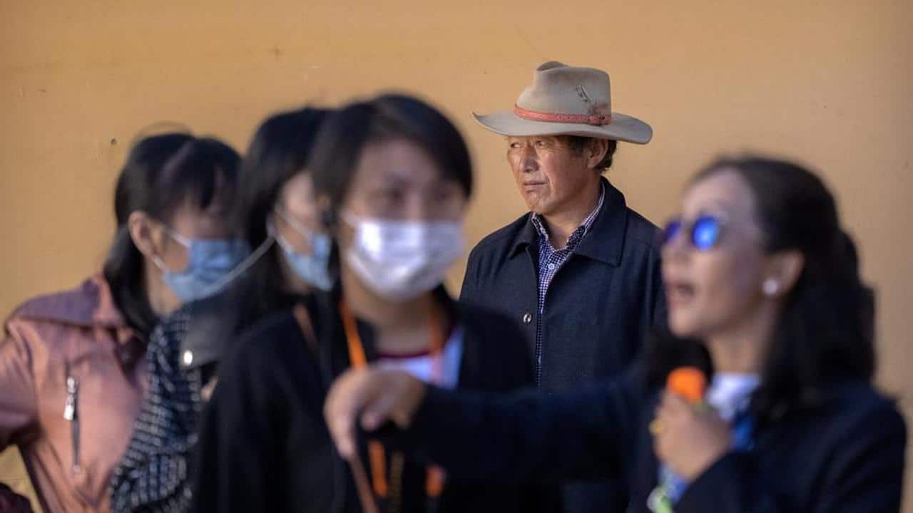 A Tibetan man stands in a courtyard as a tour guide gives a lecture to tourists at the Potala Palace in Lhasa in western China's Tibet Autonomous Region, Tuesday, June 1, 2021. Tourism is booming in Tibet as more Chinese travel in-country because of the coronavirus pandemic, posing risks to the region's fragile environment and historic sites. (AP Photo/Mark Schiefelbein) A Tibetan man stands in a courtyard as a tour guide gives a lecture to tourists at the Potala Palace in Lhasa in western China's Tibet Autonomous Region, Tuesday, June 1, 2021. Tourism is booming in Tibet as more Chinese travel in-country because of the coronavirus pandemic, posing risks to the region's fragile environment and historic sites. (AP Photo/Mark Schiefelbein)