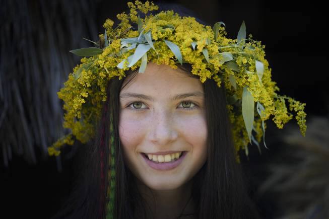A girl wearing a crown made of flowers takes part in an event inspired by pre-Christian traditions at the Dimitrie Gusti Village Museum in Bucharest, Romania, Thursday, June 24, 2021. According to pre-Christian traditions, fairies, called in Romanian &quot;Sanziene,&quot; come to earth around the summer solstice bringing fertility to land and beings for the coming summer. (AP Photo/Vadim Ghirda)