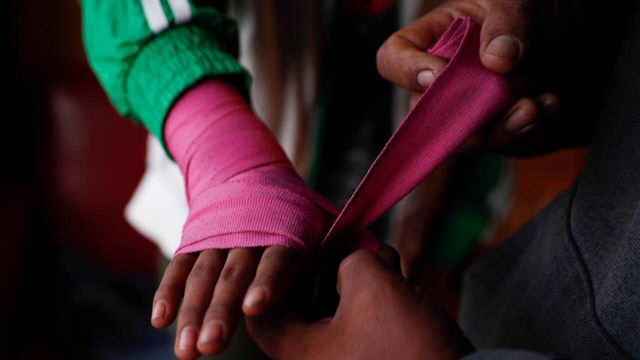 Gracce Kelly Flores is helped by her father to put bandages on her hand before starting his boxing training in Palca, Bolivia. (AP Photo/Juan Karita)