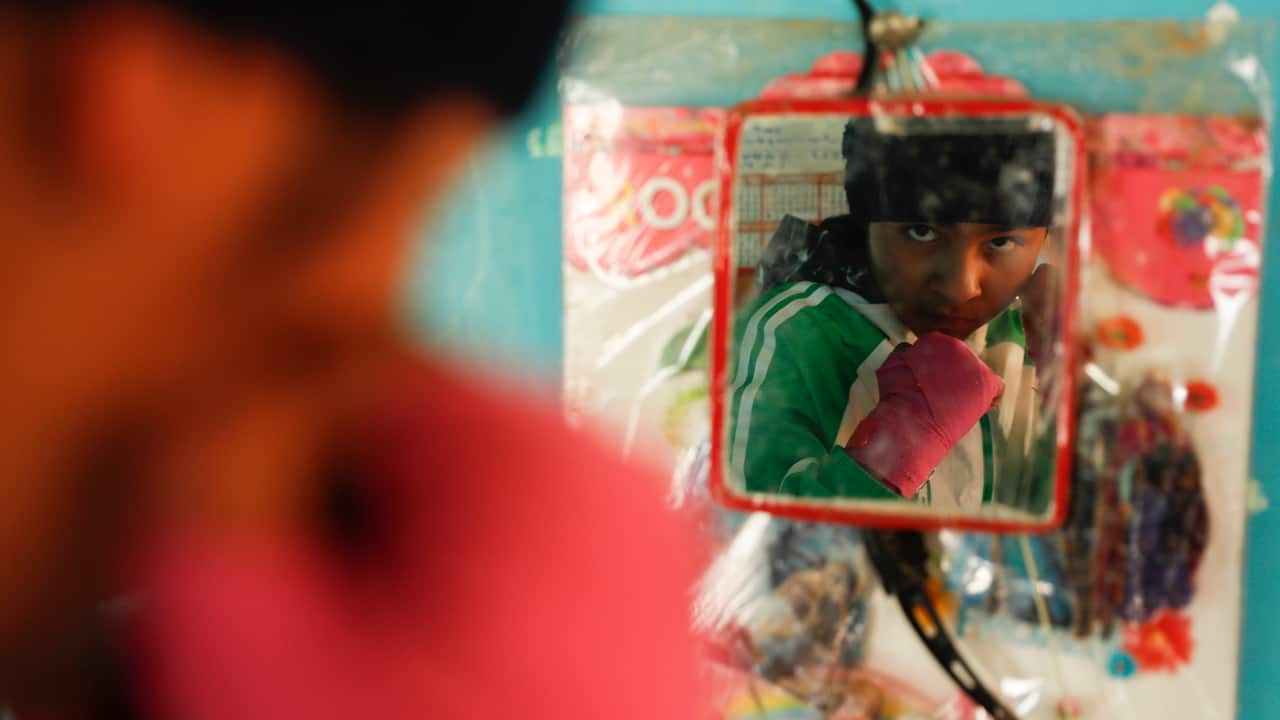 Gracce Kelly Flores strikes a pose in the mirror hanging in her kitchen after her morning workout in Palca, Bolivia. (AP Photo/Juan Karita)