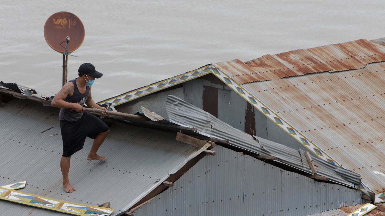 An ethnic Vietnamese man removes sheets of tin roofing from his floating house along the Tonle Sap river bank near the village of Prek Pnov in Phnom Penh, Cambodia, Saturday, June 12, 2021. (AP Photo/Heng Sinith)