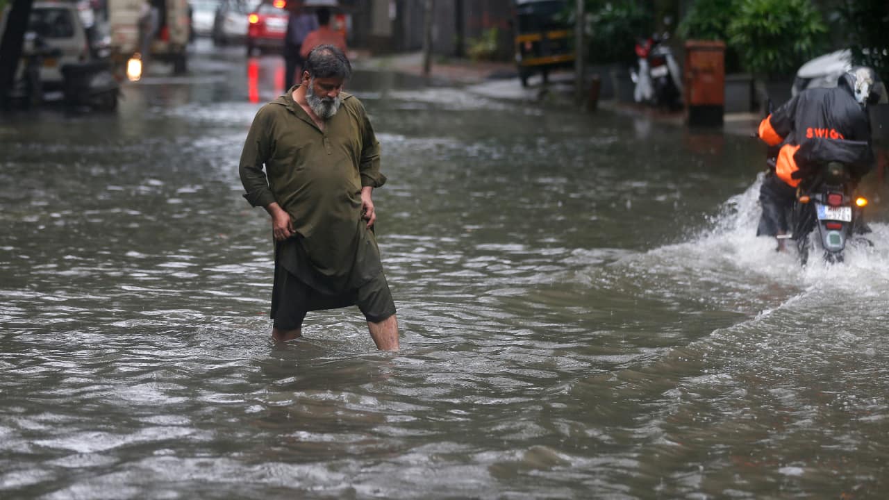 A man walks through a flooded street during heavy rains in Mumbai, India, Saturday, June 12, 2021. (AP Photo/ Rafiq Maqbool)