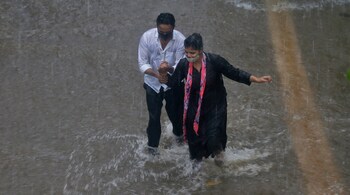 People walk through a flooded street during heavy rains in Mumbai. (AP Photo/ Rafiq Maqbool)