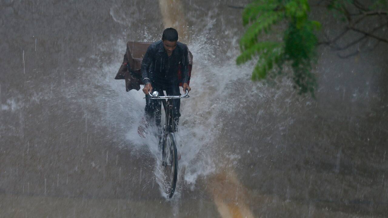 A man rides a bicycle through a flooded street during heavy rains in Mumbai. (AP Photo/ Rafiq Maqbool)