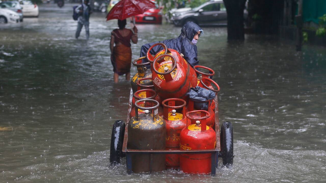 A man pushes his hand cart loaded with cooking gas cylinders through a flooded street during heavy rains in Mumbai. (AP Photo/ Rafiq Maqbool)