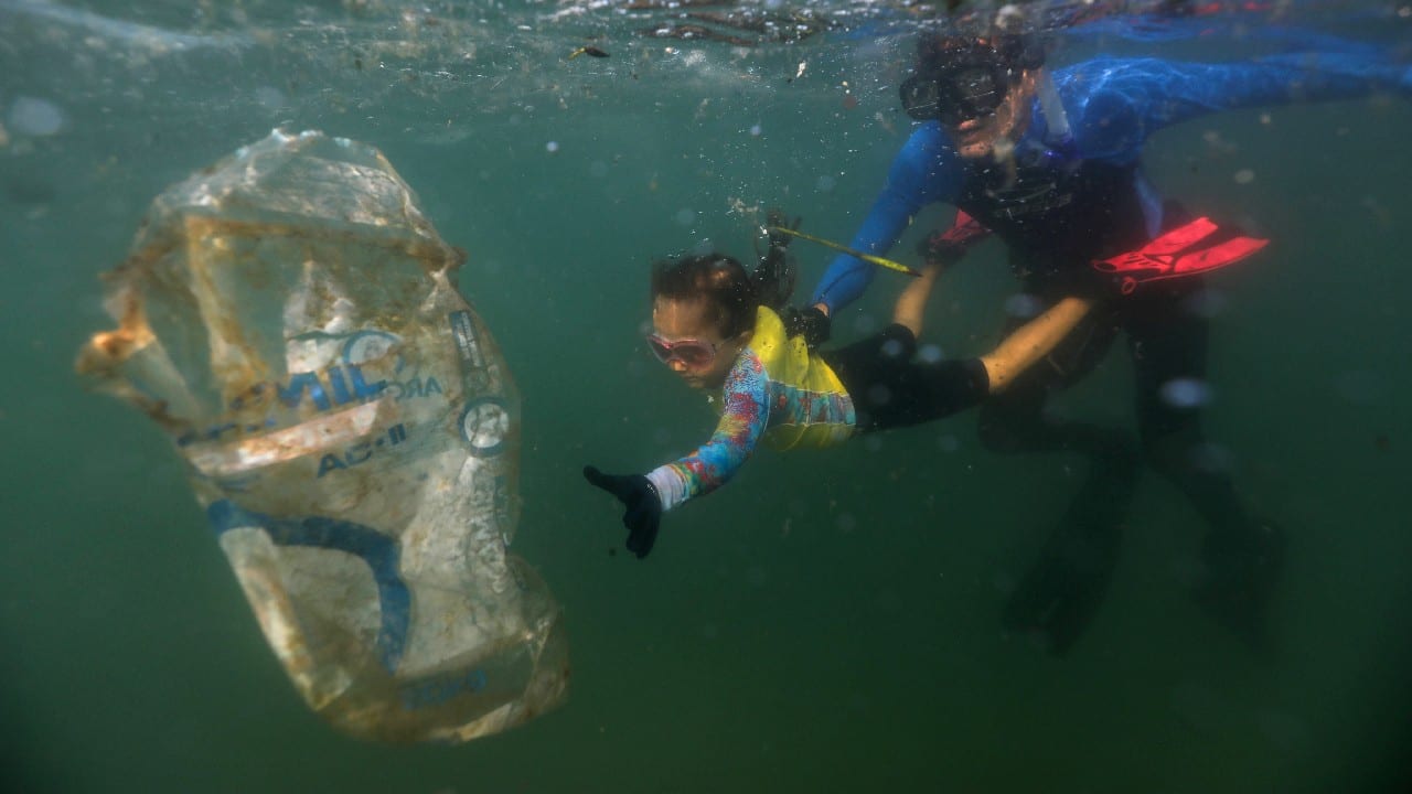 Nina Gomes is no average environmentalist. With bright pink goggles and just 4 years old, she picks trash with her father from the water along the beaches of Rio de Janeiro. (Image: Reuters)