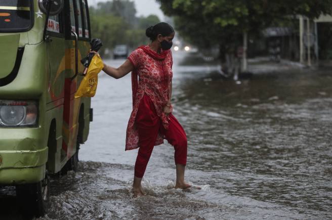 A woman alights from a bus at a flooded street during monsoon rains Jammu, India, Monday, July 12, 2021. India’s monsoon season runs from June to September. (AP Photo/Channi Anand)