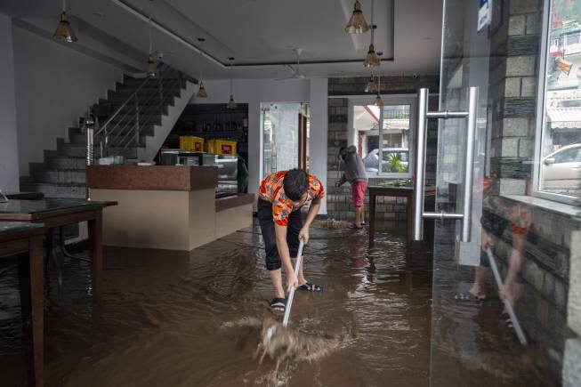 A worker mopes the waterlogged floor of a hotel after heavy monsoon rains in Bhagsunag, a popular tourist town in Himachal Pradesh, India, Monday, July 12, 2021. (AP Photo/Ashwini Bhatia)