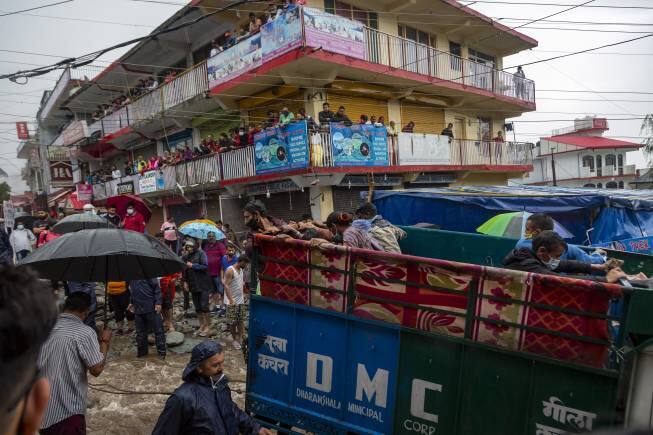 A truck carrying people helps pull a car stuck on a road during flash floods after heavy monsoon rains in Bhagsunag, a popular tourist town in Himachal Pradesh, India, Monday, July 12, 2021. (AP Photo/Ashwini Bhatia)