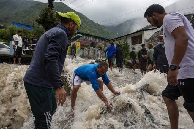 People place rocks to divert sudden gush of water during flash floods after heavy monsoon rains in Bhagsunag, a popular tourist town in Himachal Pradesh, India, Monday, July 12, 2021. (AP Photo/Ashwini Bhatia)
