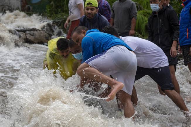 People place rocks to divert sudden gush of water during flash floods after heavy monsoon rains in Bhagsunag, a popular tourist town in Himachal Pradesh, India, Monday, July 12, 2021. (AP Photo/Ashwini Bhatia)