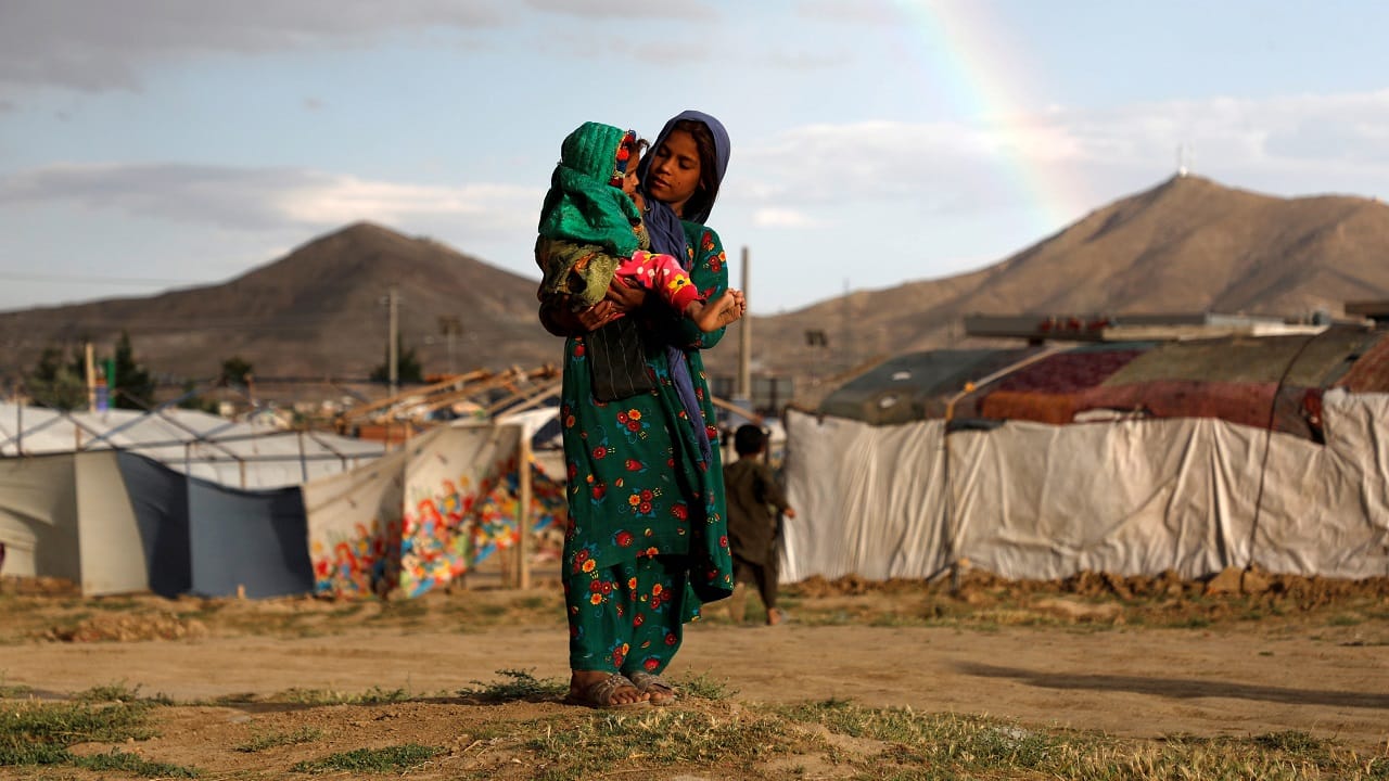 An internally displaced Afghan girl carries a child near their shelter at a refugee camp on the outskirts of Kabul on June 20, 2019 (Image: Reuters/Omar Sobhani)