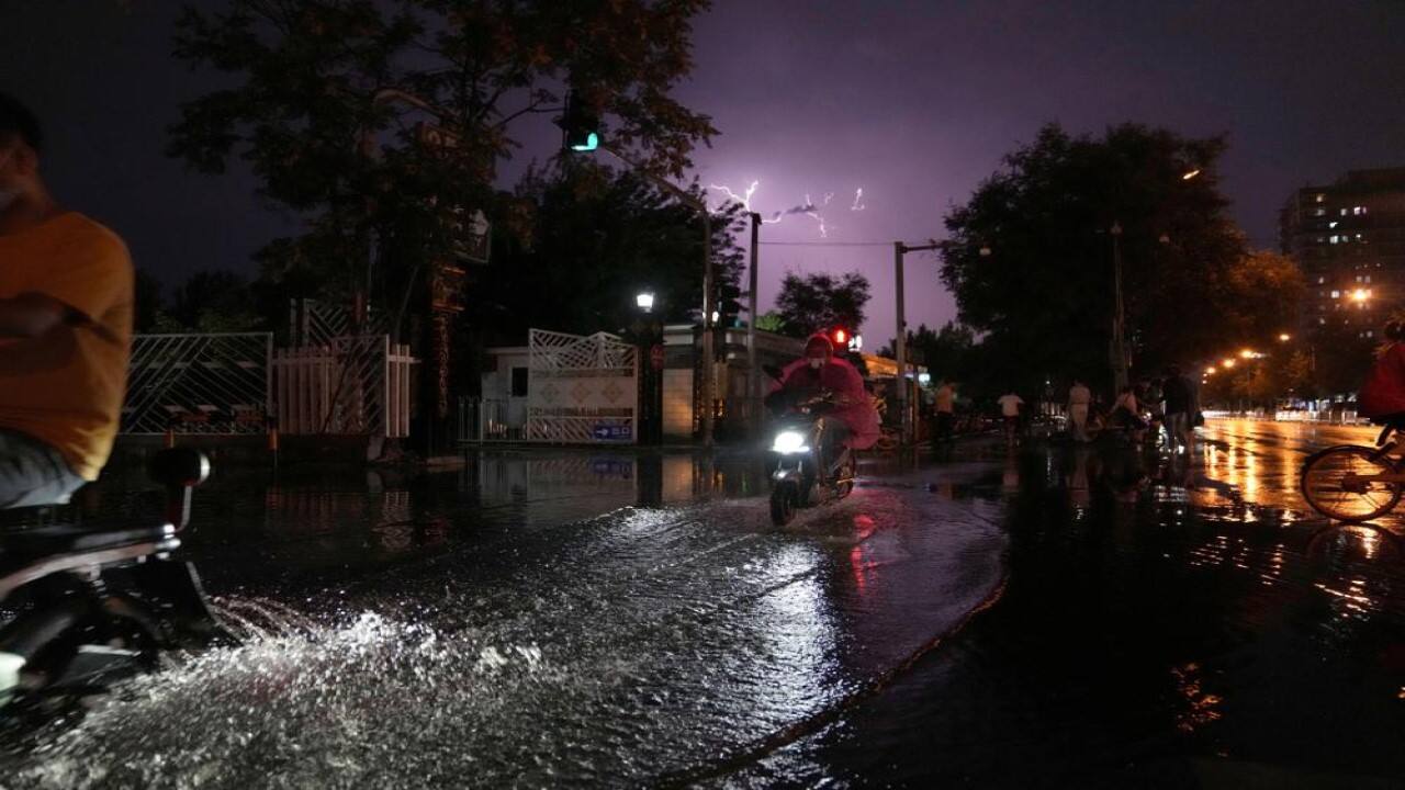Residents past through a flooded section of a road during a thunderstorm in Beijing, China, Monday, Aug. 9, 2021. (Image: AP)
