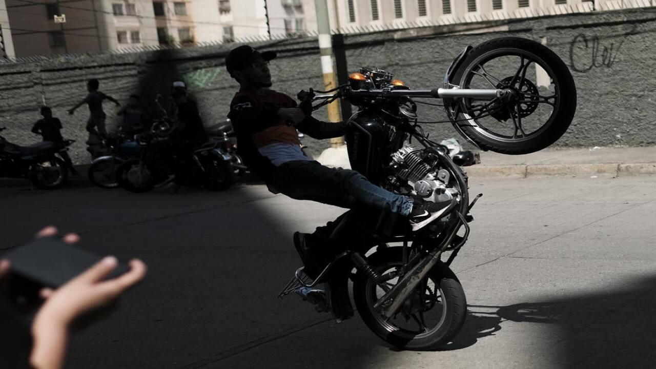 A motorcyclist performs a wheelie on his motorbike during an exhibition in the El Valle neighborhood of Caracas, Venezuela, Saturday, July 31, 2021. (Image: AP)
