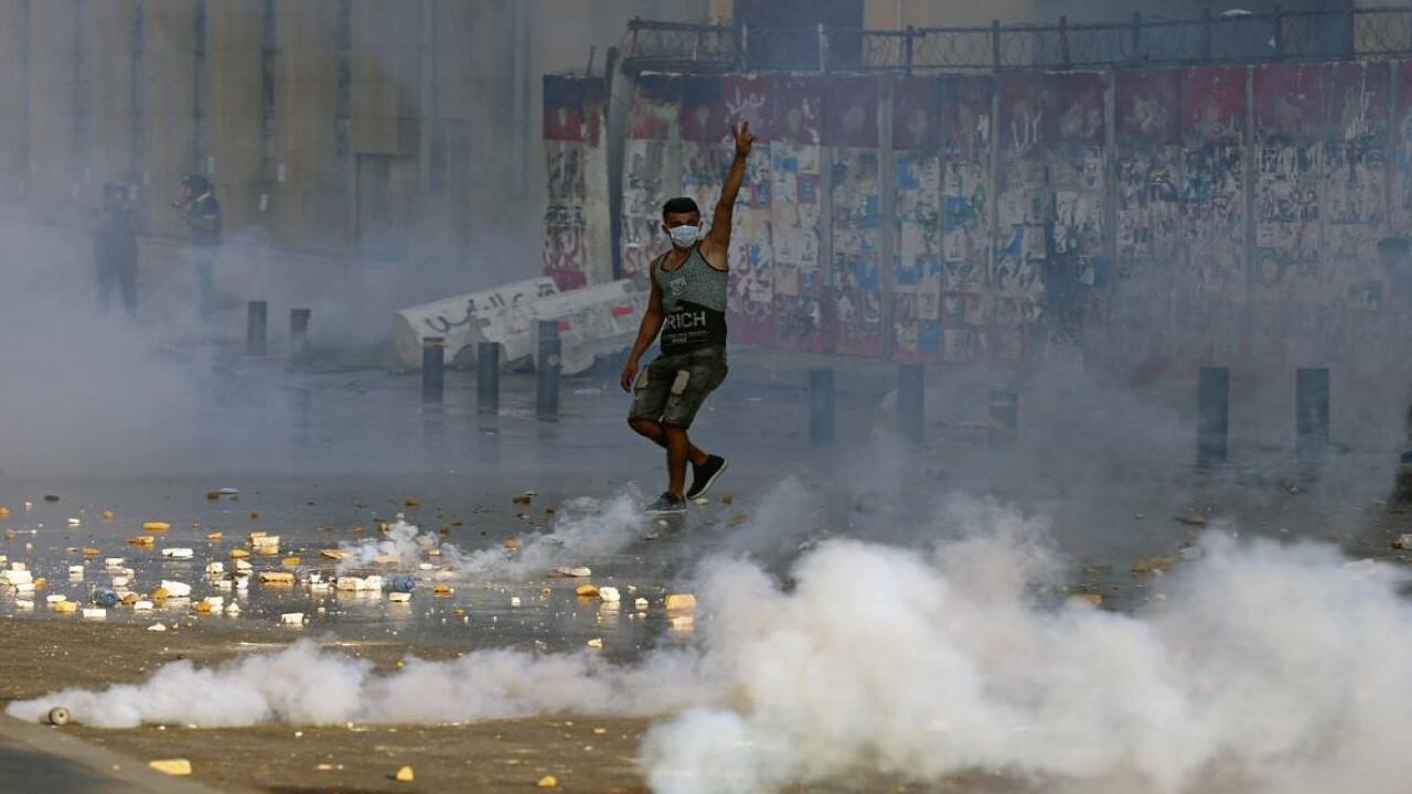 An anti-government protester flashes the victory sign amid tear gas fired by riot police during a protest marking the first anniversary of the massive blast at Beirut's port, near Parliament Square, In Beirut, Lebanon, Wednesday, Aug. 4, 2021. United in grief and anger, families of the victims and other Lebanese came out into the streets of Beirut on Wednesday to demand accountability as banks, businesses and government offices shuttered to mark one year since the horrific explosion. (Image: AP)