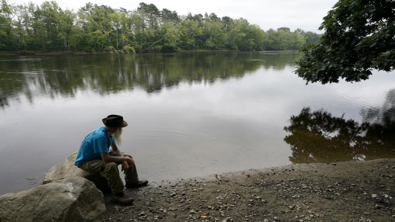 David Lidstone, 81, sits near the Merrimack River, Tuesday, Aug. 10, 2021, in Boscawen, N.H. Lidstone, an off-the-grid New Hampshire hermit known to locals as &quot;River Dave,&quot; had been living in a cabin in the woods along the Merrimack River, in Canterbury, N.H., for nearly three decades. He was jailed July 15, 2021 on a civil contempt sanction and was told he'd be released if he agreed to leave the cabin, that has since burnt down. (Image: AP)