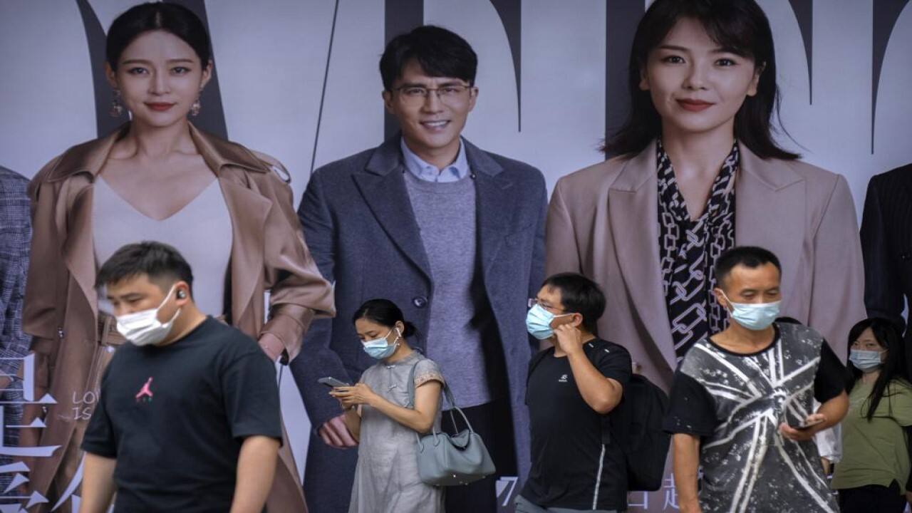 People wearing face masks to help protect against COVID-19 walk past an advertising billboard at a subway station during the morning rush hour in Beijing, Wednesday, Aug. 4, 2021. China's worst coronavirus outbreak since the start of the pandemic a year and a half ago escalated Wednesday with dozens more cases around the country, the sealing-off of one city and the punishment of its local leaders. (Image: AP)