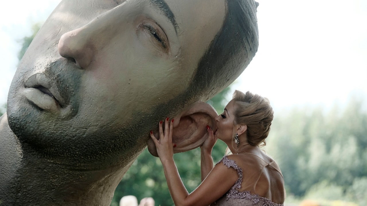 A woman touches sculpture "Lowers" during a flower festival in Pakruojis, Lithuania August 14. (Image: Reuters)