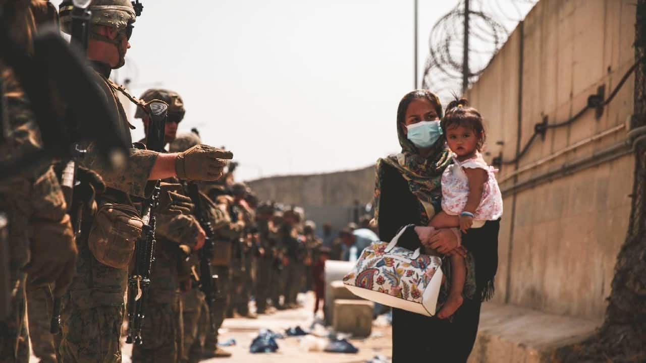 A U.S. Marine assigned to 24th Marine Expeditionary Unit guide an evacuee during an evacuation at Hamid Karzai International Airport, Afghanistan, August 18. (Image: U.S. Marine Corps/Reuters)