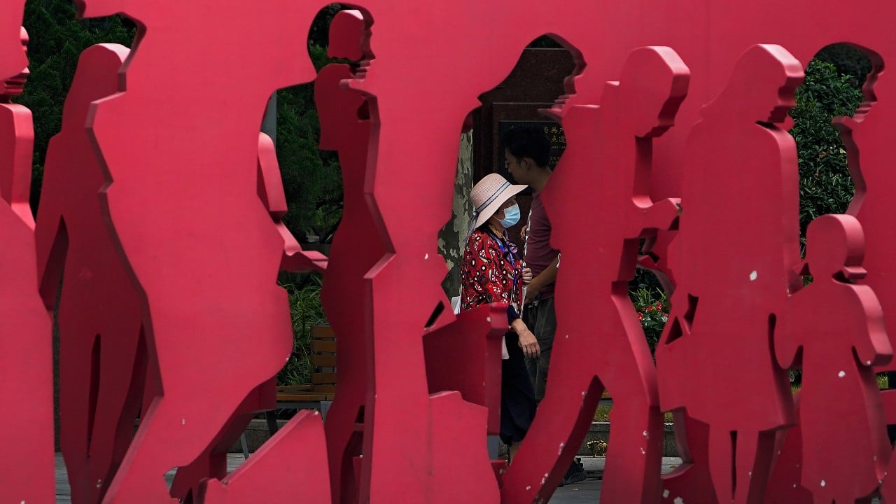 A woman wearing a face mask to help protect from the coronavirus walks by an art installation depicting people along a street in Shanghai, China, August 24. (Image: AP)
