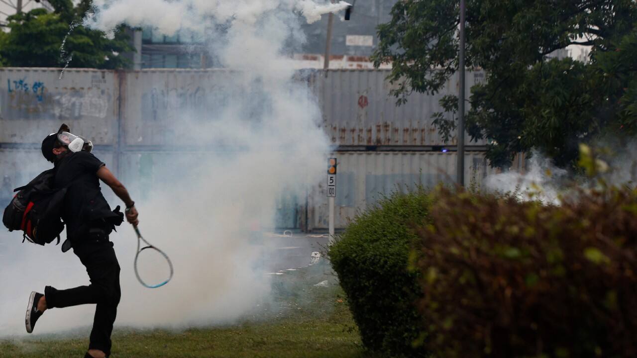 An anti-government protester knocks back tear gas fired by riot police during a protest in Bangkok, Thailand, August 13. Protesters demanded the resignation of Prime Minister Prayuth Chan-ocha for what they say is his failure in handling the COVID-19 pandemic. (Image: AP)