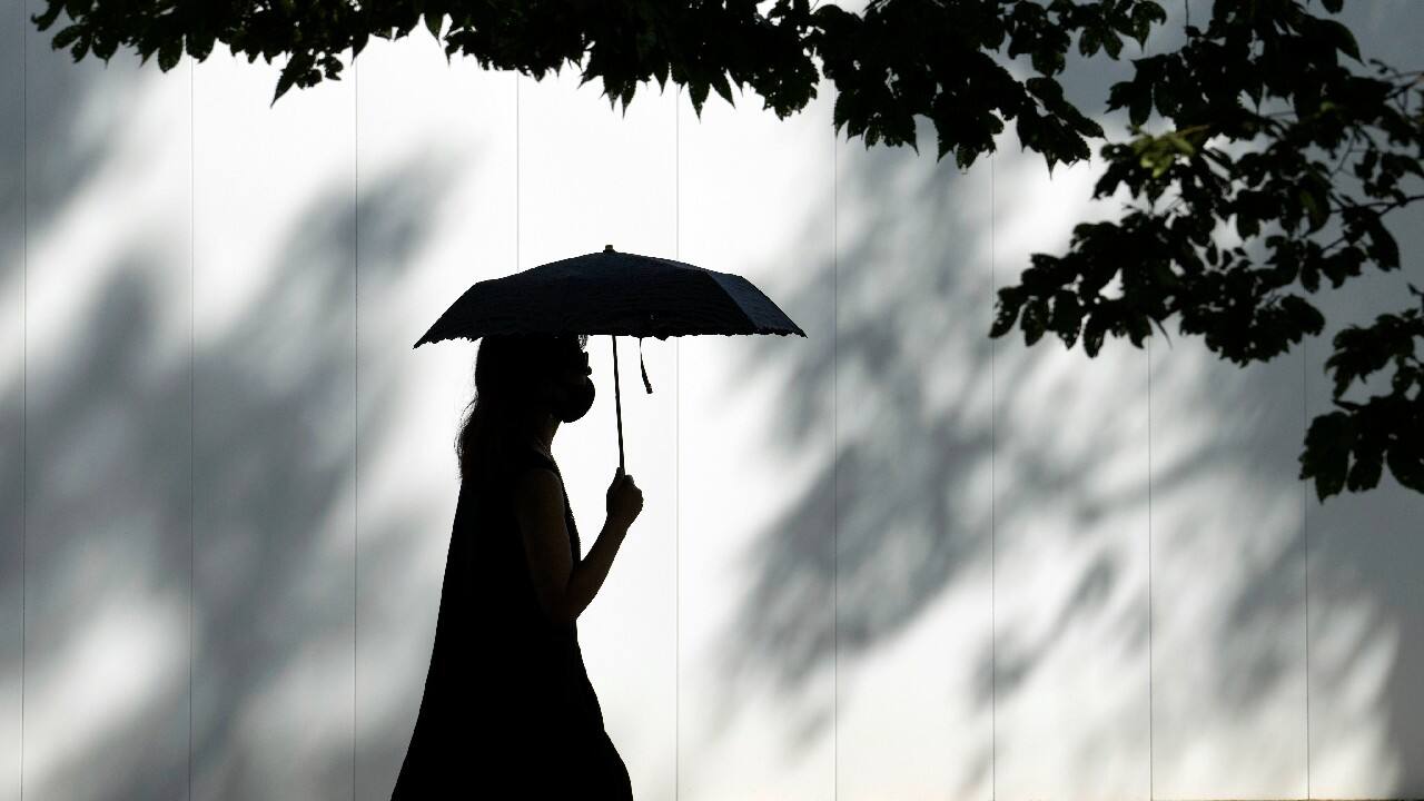 A woman wearing a face mask to help protect against the spread of the coronavirus walks under the scorching sun in Tokyo, Japan. (Image: AP)