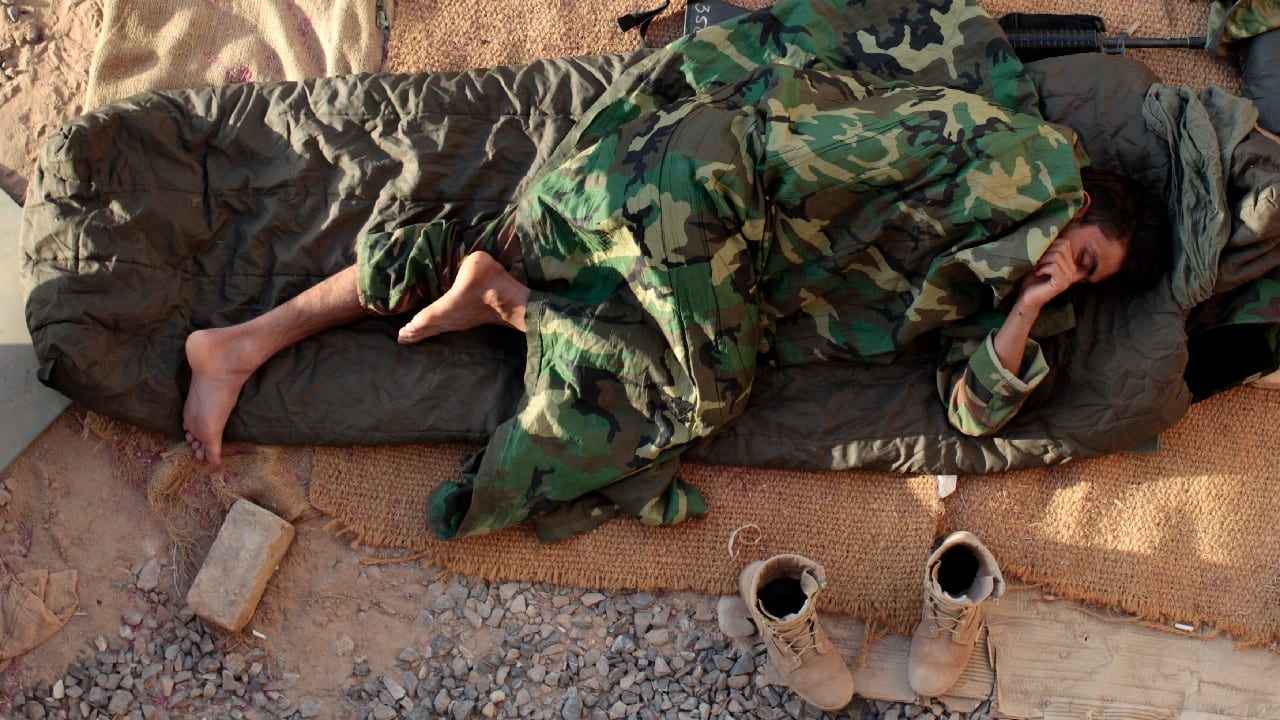 Afghan national army soldier sleeps outdoors during sunrise at their compound inside at Panjwai district in Kandahar, May 31, 2009. (Image: Reuters)