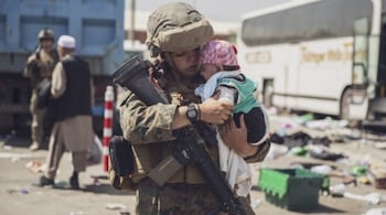 A US Marine with the 24th Marine Expeditionary Unit (MEU) carrying a baby as the family processes through the Evacuation Control Center (ECC) during an evacuation at Hamid Karzai International Airport, Kabul, Afghanistan, on August 28, 2021. US service members are assisting the Department of State with a non-combatant evacuation operation (NEO) in Afghanistan. (Victor MANCILLA / US MARINE CORPS/AFP)