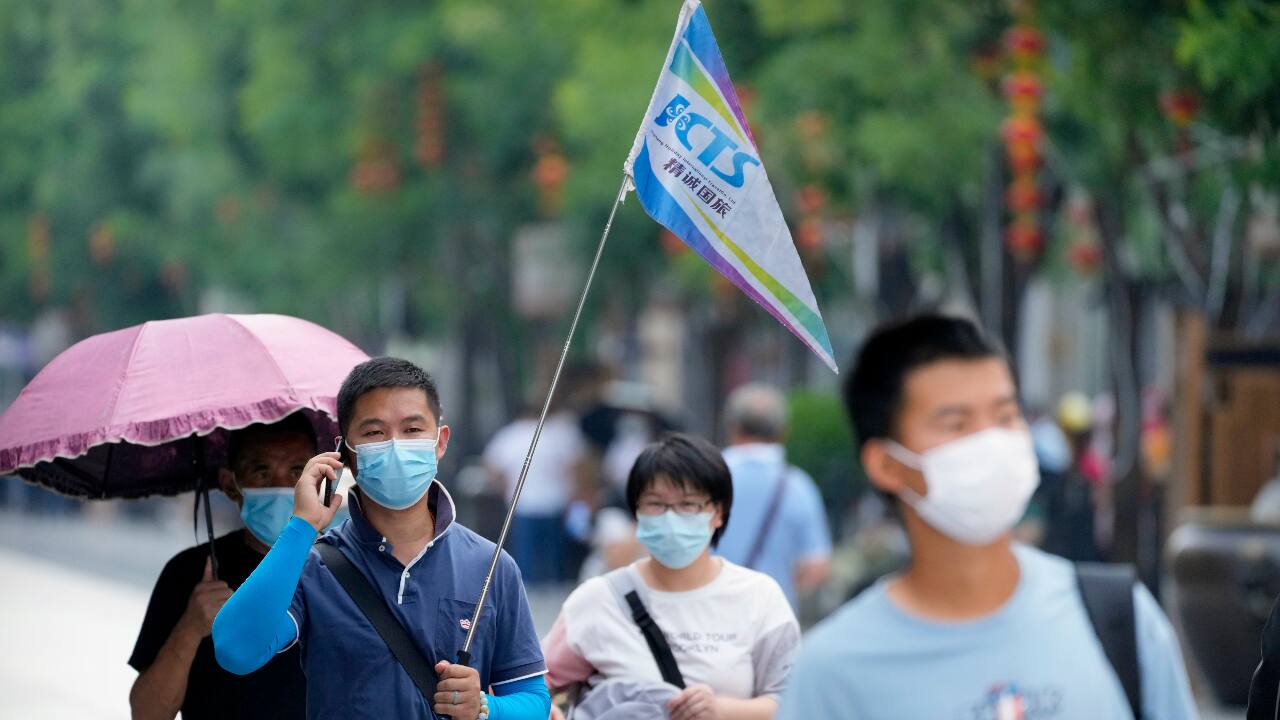 A tour guide carries a flag as he walks along a pedestrian street in a neighborhood popular with tourists in central Beijing. (AP Photo/Mark Schiefelbein)