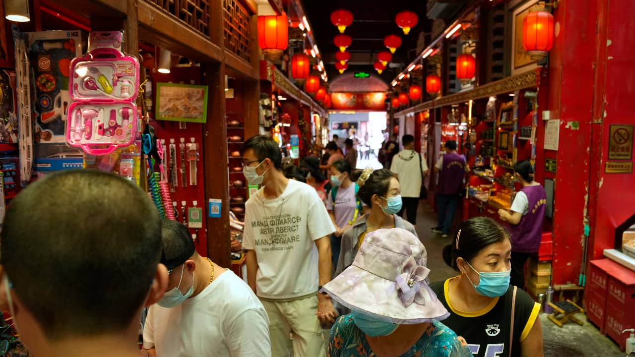 Visitors wearing face masks look at souvenir shops in a neighborhood popular with tourists in central Beijing. (AP Photo/Mark Schiefelbein)