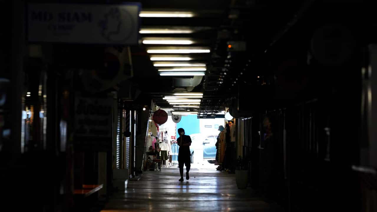 A person walks through closed shops in Siam Square, a famous shopping district in Bangkok, Thailand. (AP Photo/Sakchai Lalit)