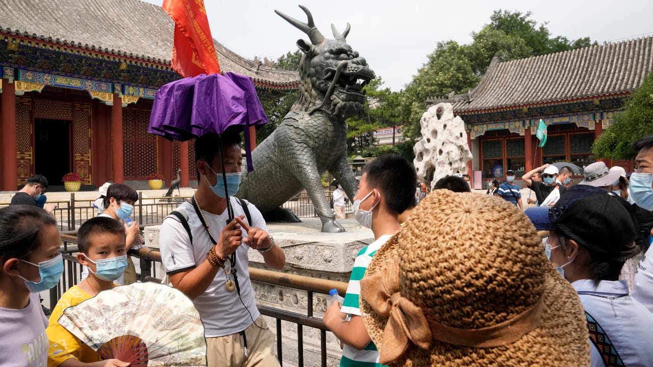 A tour guide leads a group of domestic tourists visiting the Summer Palace in Beijing on August 3, 2021. (AP Photo/Ng Han Guan)
