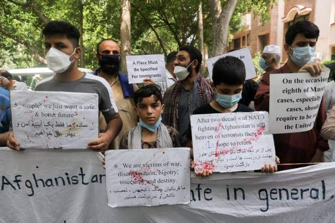 People hold signs as they protest outside the United Nations High Commissioner for Refugees (UNHCR) office to urge the international community to help Afghan refugees, in New Delhi, India, August 23, 2021. REUTERS/Anushree Fadnavis - RC2TAP91VN5B