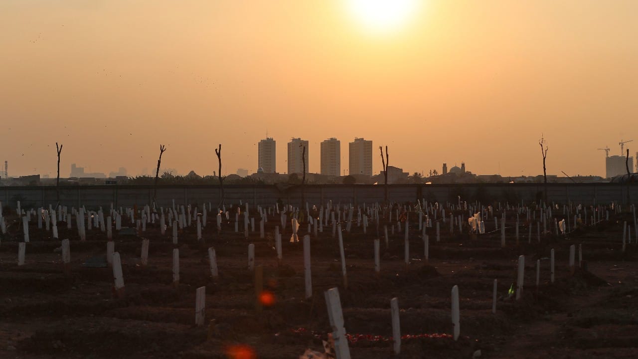 In the Muslim section, flowers and flat wooden grave markers catch the sun’s last rays. A sturdy black sign declares these COVID-19 casualties to be “syuhada” — a common Indonesian spelling of the Arabic word for martyrs. A young man in a facemask sits on the ground beside a nearby grave, his fingers knitted together, seemingly lost in thought as the light fades toward dusk. (Image: AP) In the Muslim section, flowers and flat wooden grave markers catch the sun’s last rays. A sturdy black sign declares these COVID-19 casualties to be “syuhada” — a common Indonesian spelling of the Arabic word for martyrs. A young man in a facemask sits on the ground beside a nearby grave, his fingers knitted together, seemingly lost in thought as the light fades toward dusk. (Image: AP)