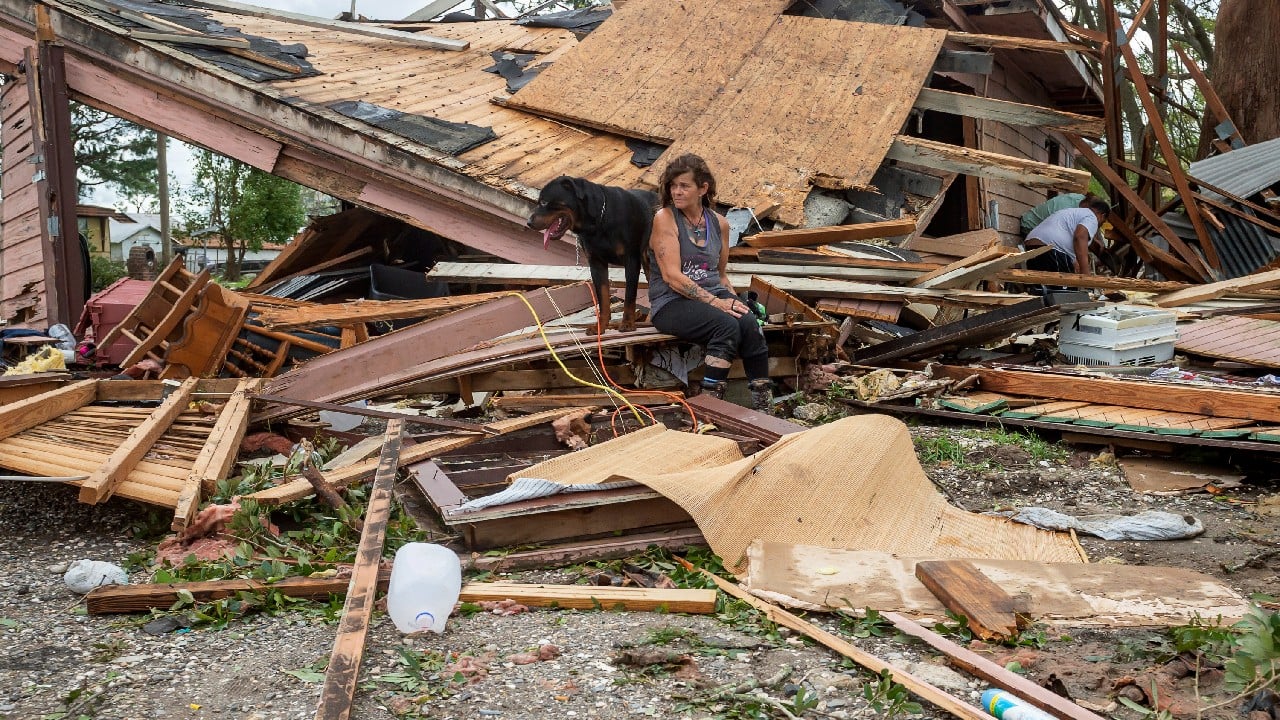 Fran Tribe and her dog, Dave, sit outside a home destroyed by Hurricane Ida in Houma, La., on August 30. (Image: AP)