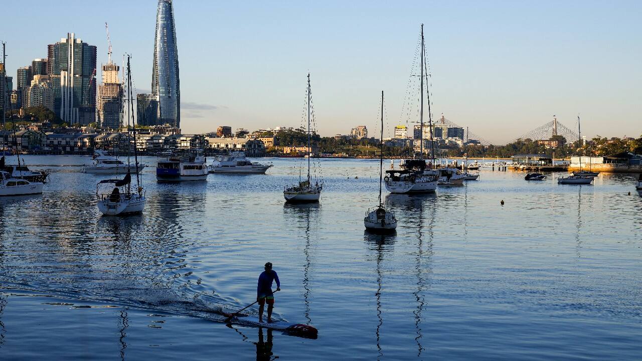 A man paddles on his stand up paddle board in the early morning on Sydney Harbour Australia. (Image: AP)