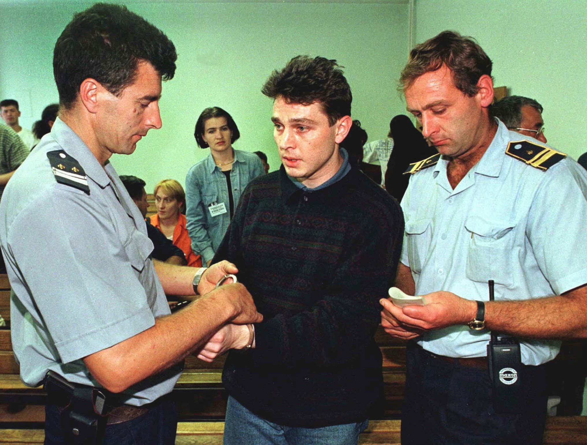 FILE - In this July 16, 1997 file photo, police handcuff Lionel Dumont of France after his trial in central Bosnian town of Zenica for a series of robberies in Bosnia. Dumont, a senior al-Qaida member, was based in Japan for more than a year, and investigators suspect he was trying to establish a terror cell, Japanese media said Tuesday, May 18, 2004. (AP Photo/Hidajet Delic, File)