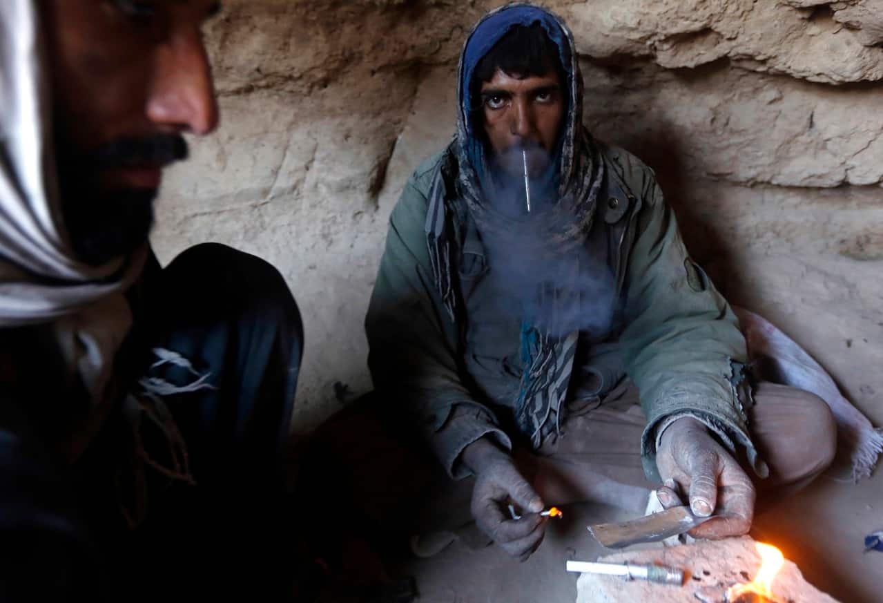 A drug addict smokes heroin inside a cave in Farah province, on February 4, 2015. (Image: Reuters/Omar Sobhani)