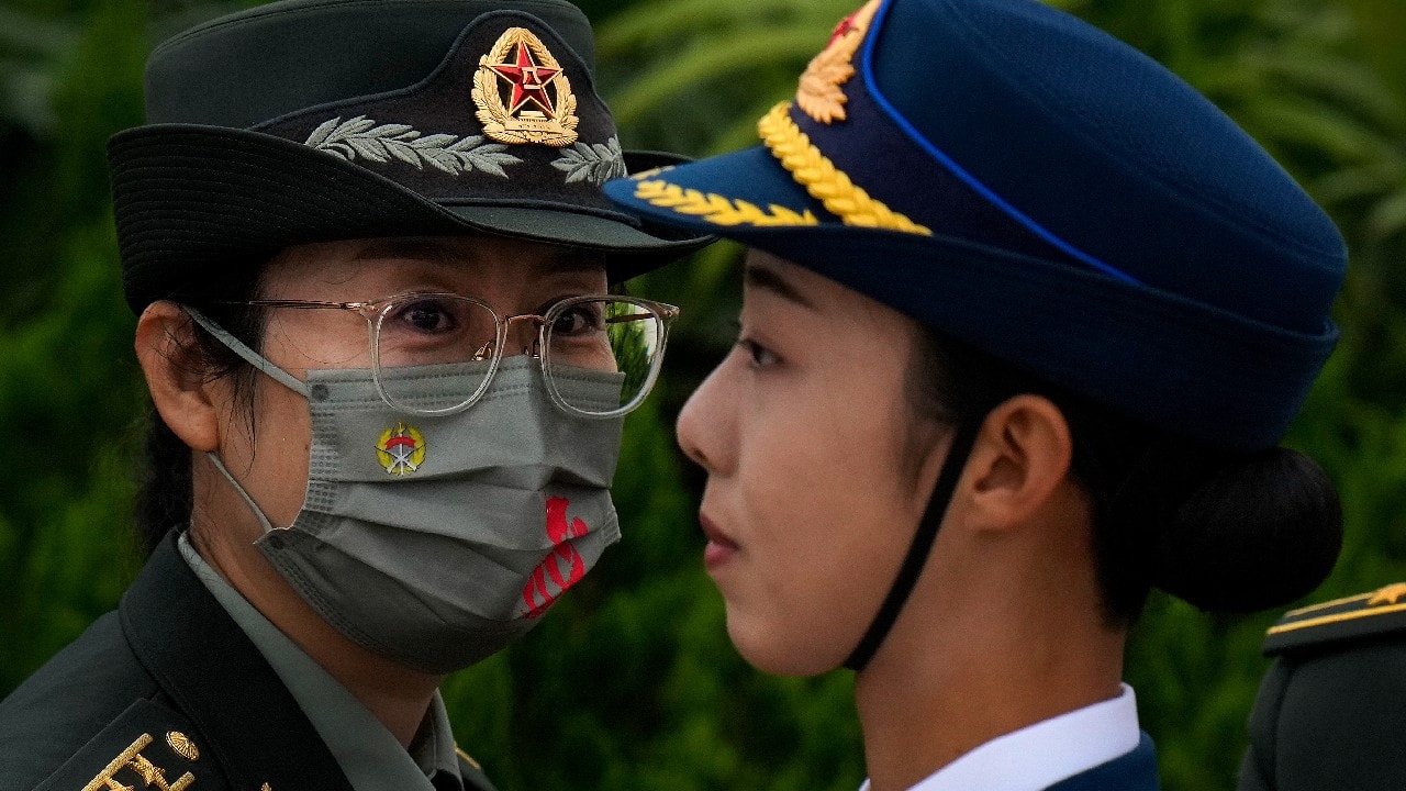 A female military officer wearing a face mask to help protect from the coronavirus looks at a female honor guard stands on Tiananmen Square during a ceremony to mark Martyr's Day in Beijing, September 30. (Image: AP)